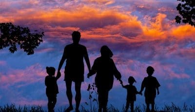 Family in the sunset walking hand-in-hand.